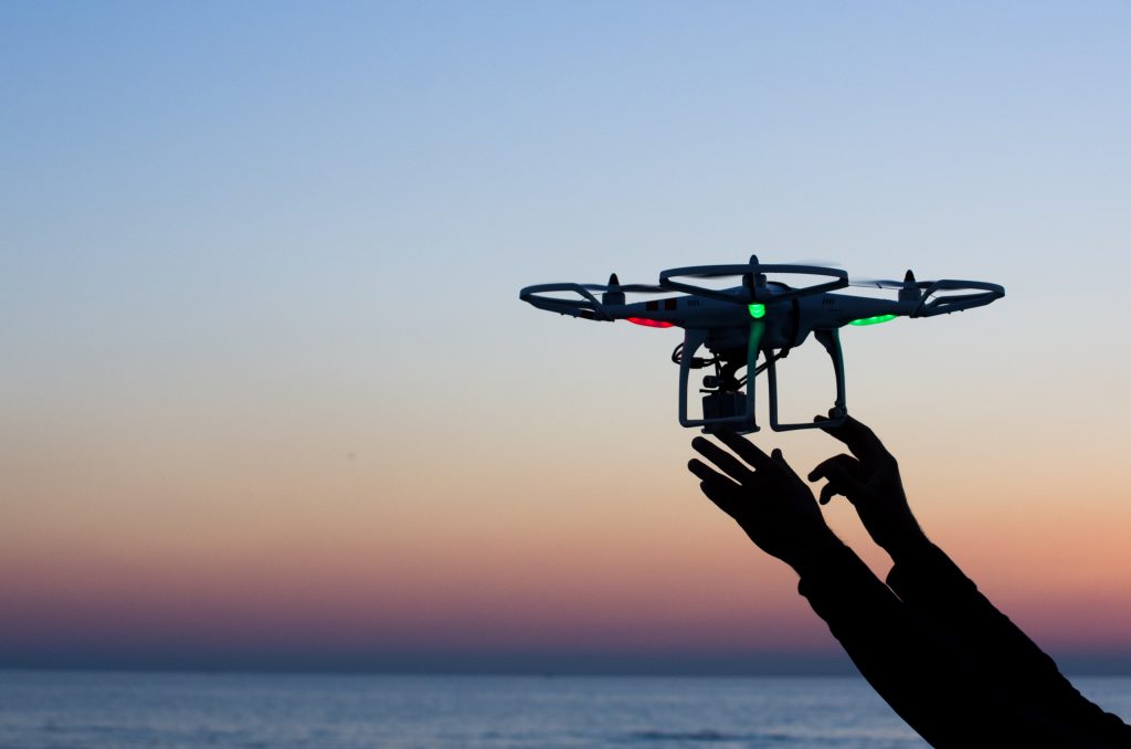 Flying drone with camera on the sky at sunset